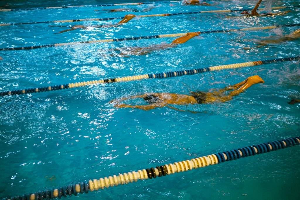Indoor swimming competition with swimmers racing in lanes under artificial lighting.